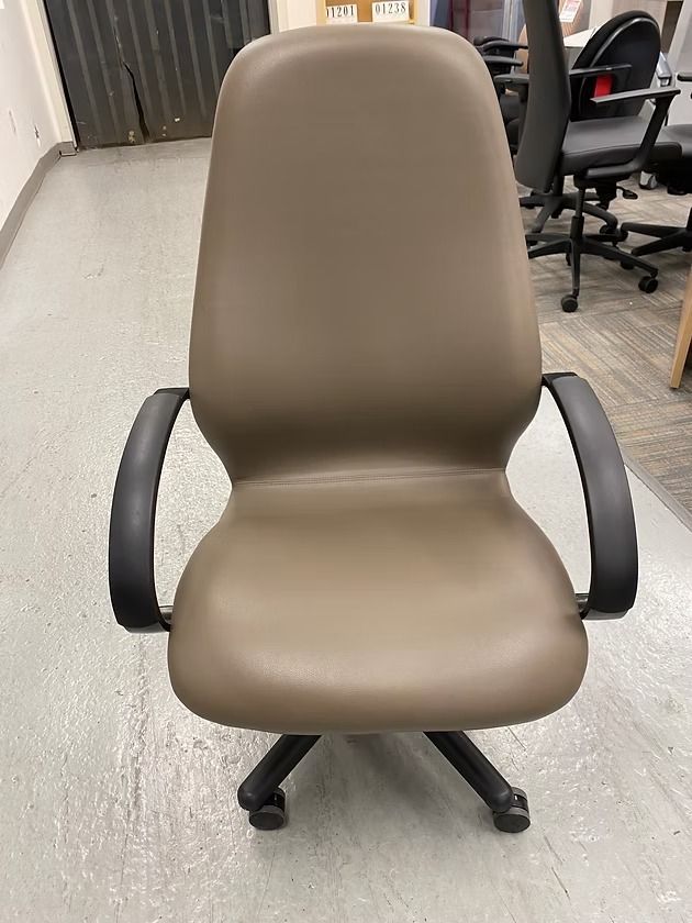 Brown office chair with black arms and base, on a concrete floor.