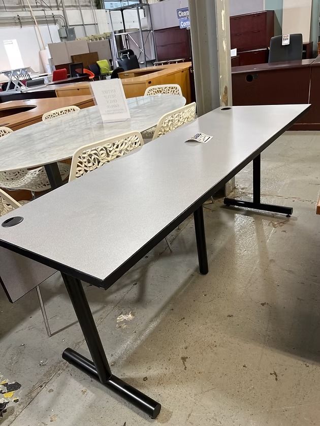 Long gray rectangular table with black legs, in a warehouse setting.