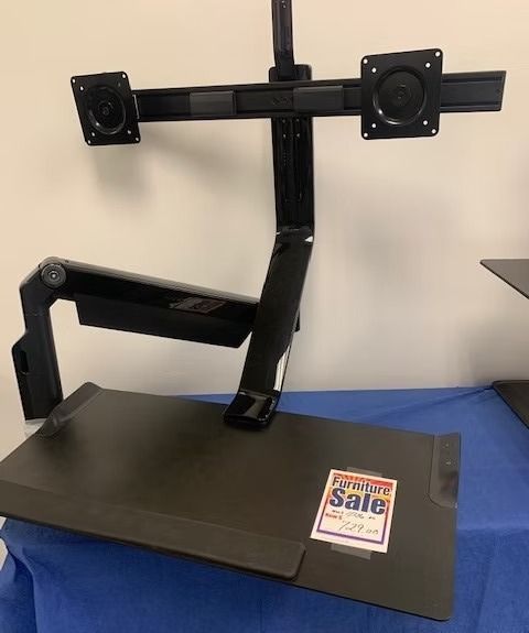 Black adjustable desk with dual monitor mount;