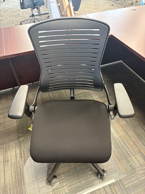 Black office chair with a mesh back and padded seat, in front of a desk.