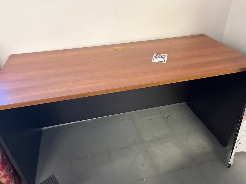 Brown and black office desk against a light-colored wall, with cards on top.