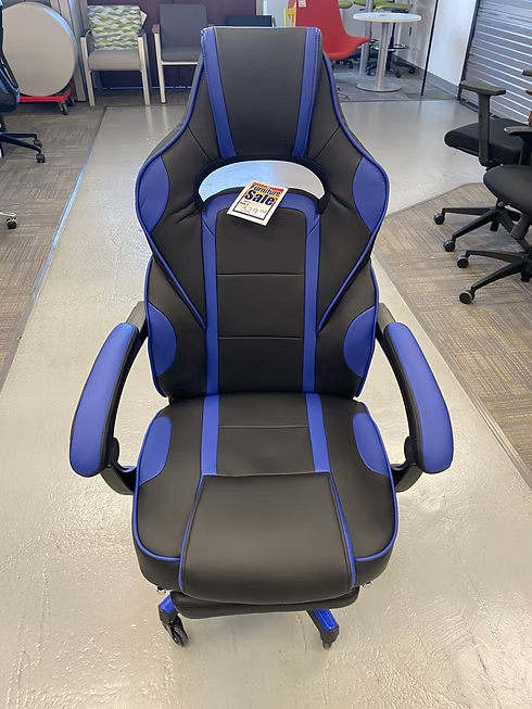 Black and blue gaming chair on a light-colored floor, with arms and a tall backrest.