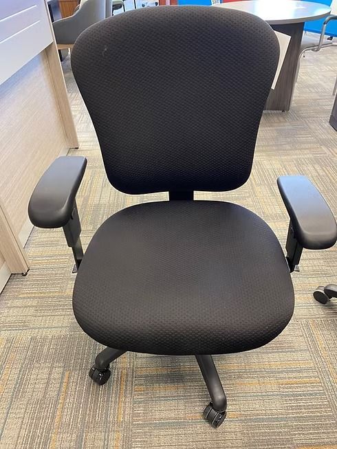 Black office chair with padded seat, back, and armrests on a carpeted floor.