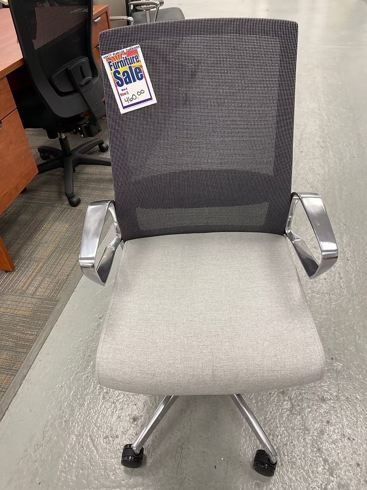 Gray and black office chair with mesh back, chrome arms, and five-star base. Sale tag attached.