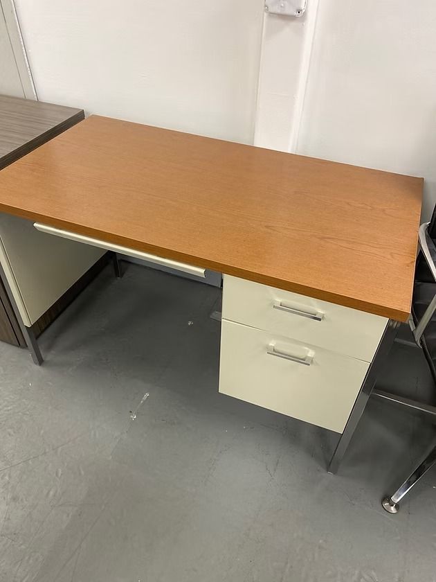 Office desk with a wood-grain top, white drawers, and chrome legs.