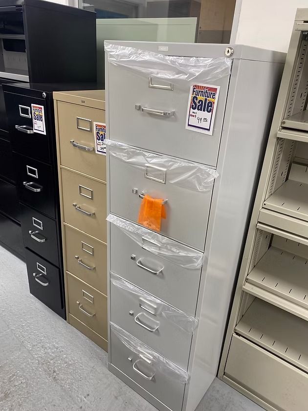 File cabinets in black, tan, and gray lined up for sale in a store.