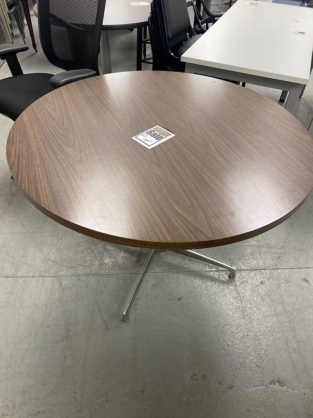 Round brown table with a metal base, in a room with other office furniture.