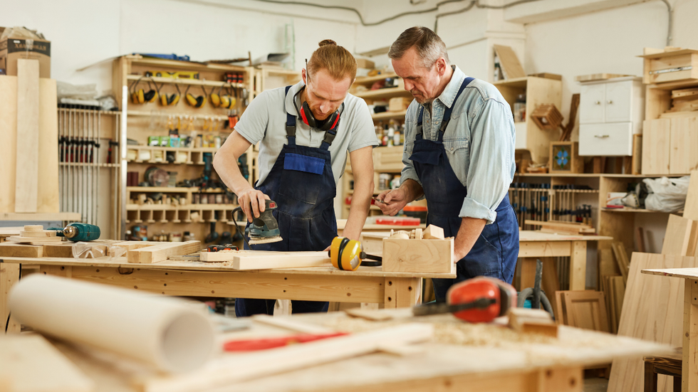 Two woodworkers examining a wooden project in a workshop.