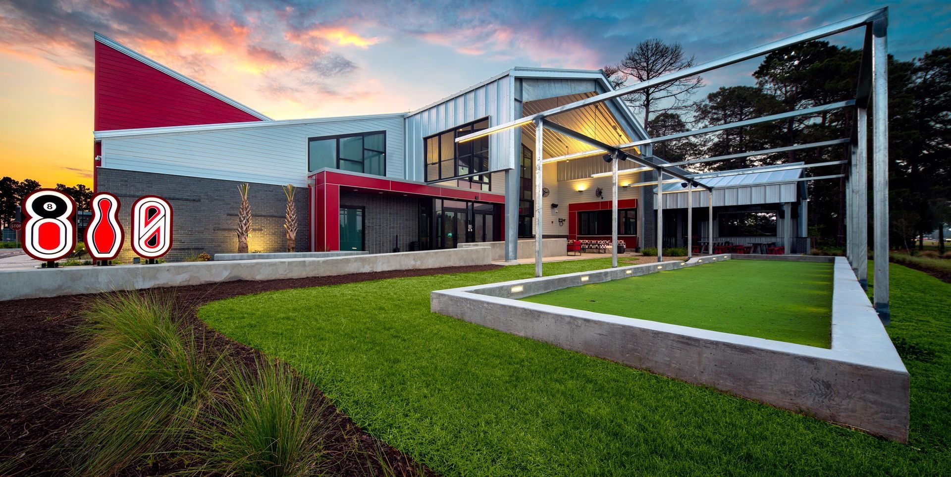 Modern building with red accents and outdoor space, grass, and bowling pin signage.