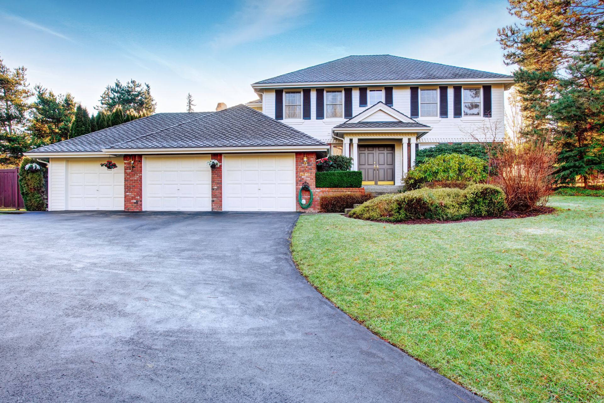 A large house with two garage doors and a driveway leading to it.