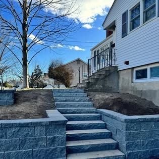 Stone steps leading up to a white house with a wrought iron railing, under a blue sky.