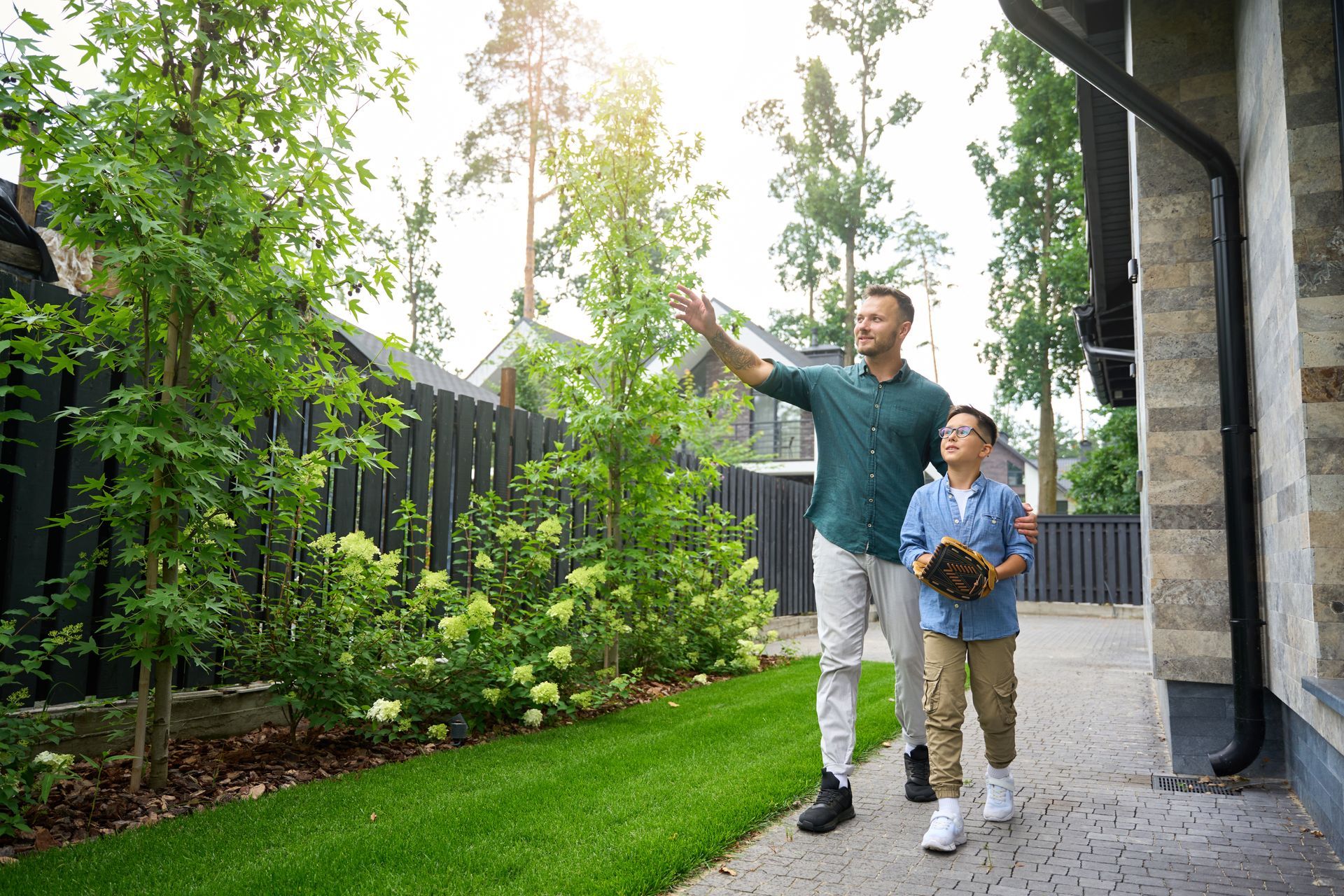 Man using a shovel to put dirt in a hole, with potted trees in background on pallet.
