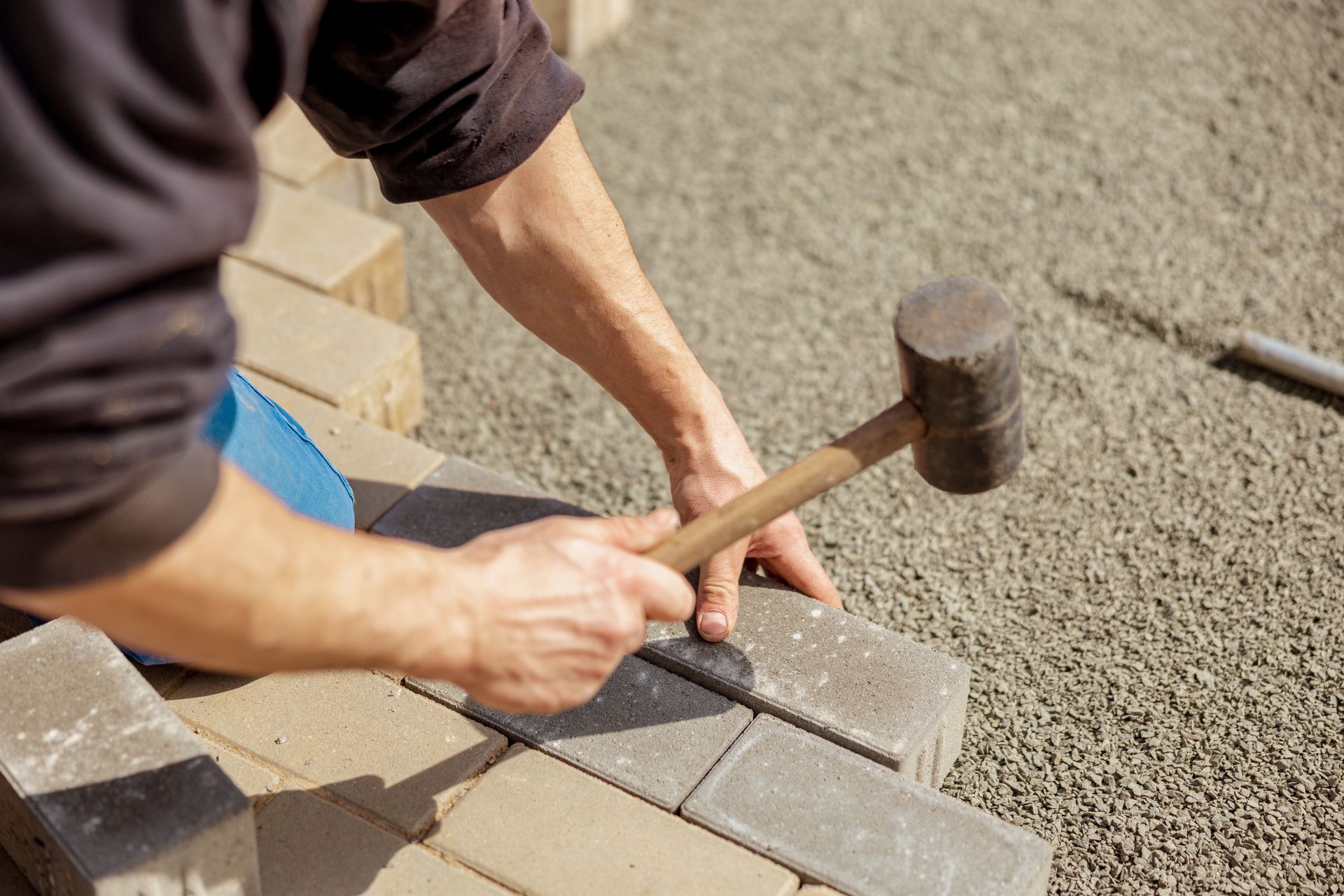 Person using a mallet to install paving stones.