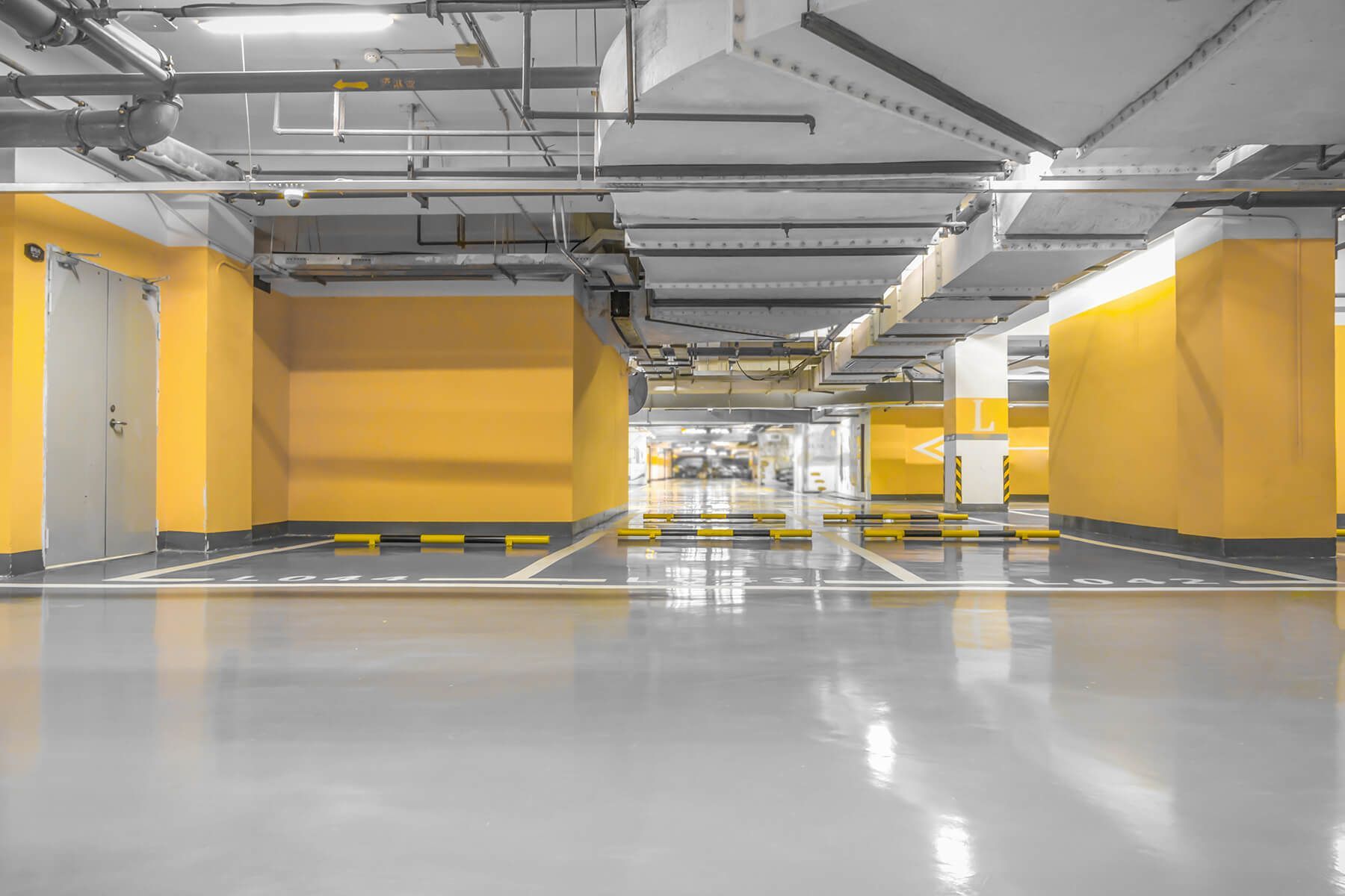 an empty underground parking garage with yellow walls and a concrete floor .