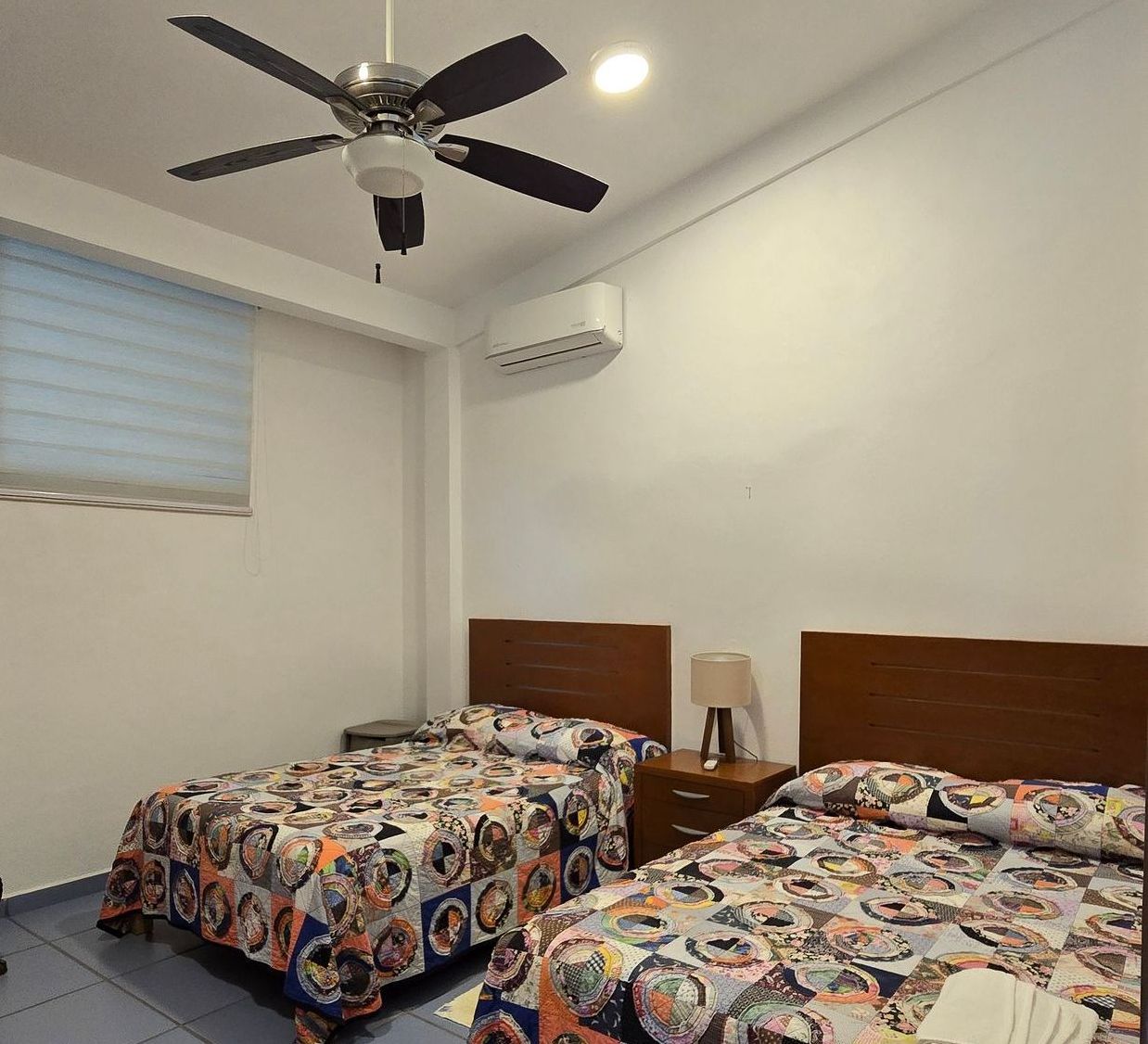 Un dormitorio con dos camas y un ventilador de techo.