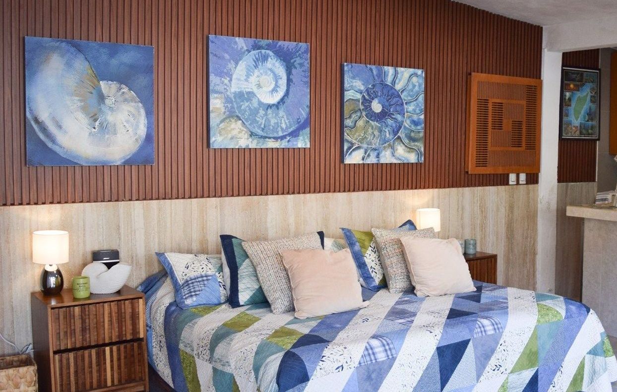 Un dormitorio con una cama y tres cuadros en la pared.