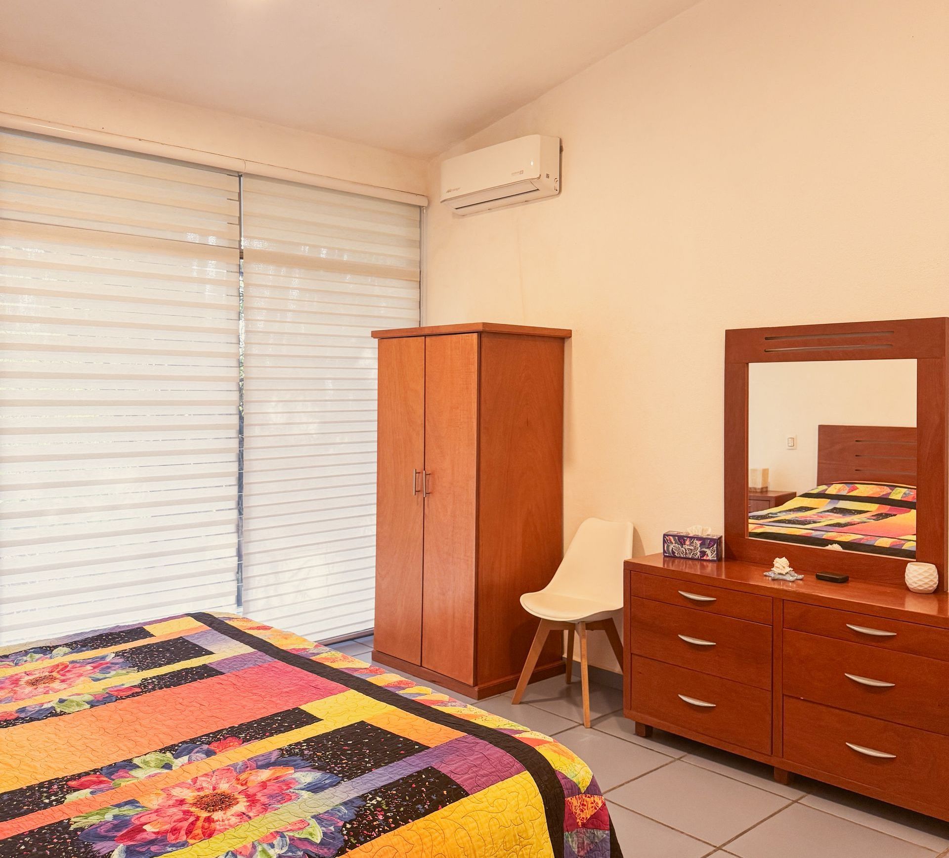 Un dormitorio con una cama, tocador y espejo.