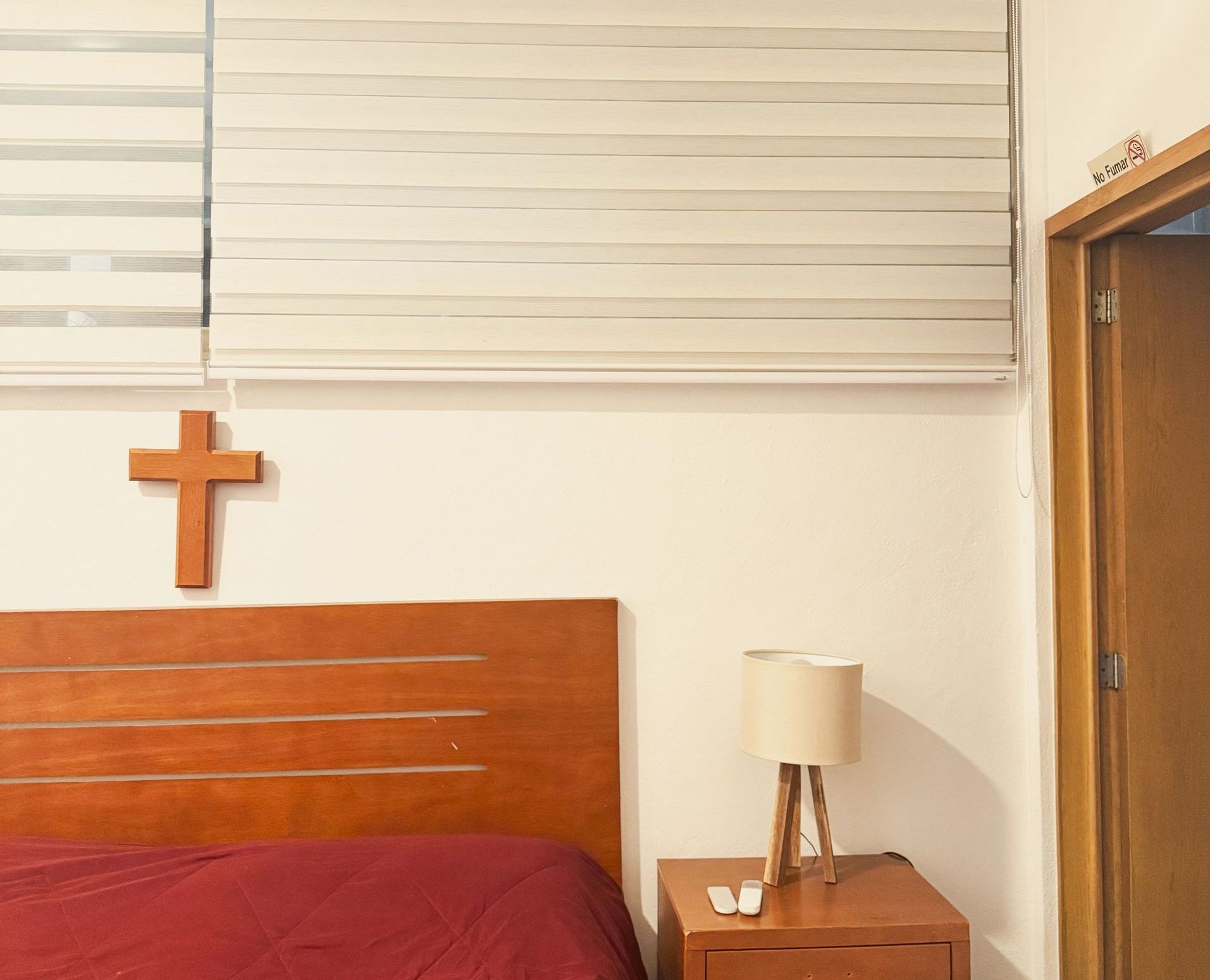 Un dormitorio con una cruz en la pared encima de la cama.
