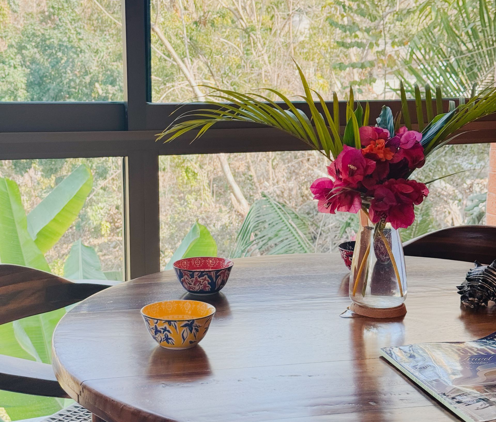 Una mesa con un jarrón de flores y cuencos encima.