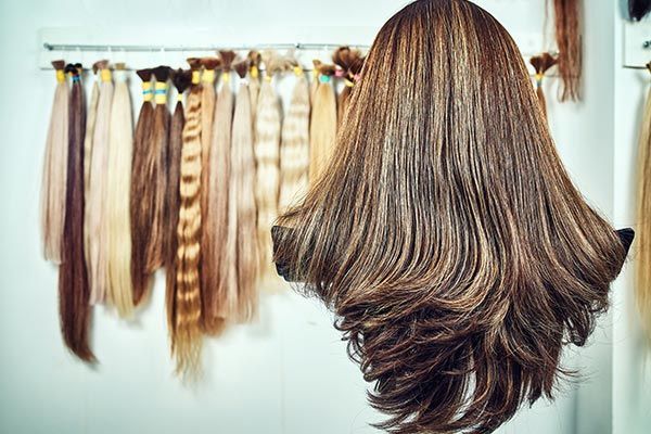 A wig is hanging in front of a bunch of hair extensions.