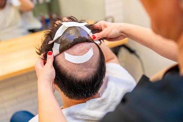 A woman is cutting a man 's hair in a salon.