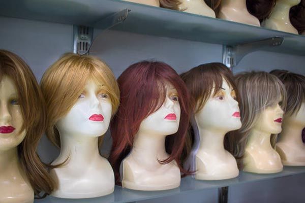 A row of mannequin heads with wigs on them on a shelf.