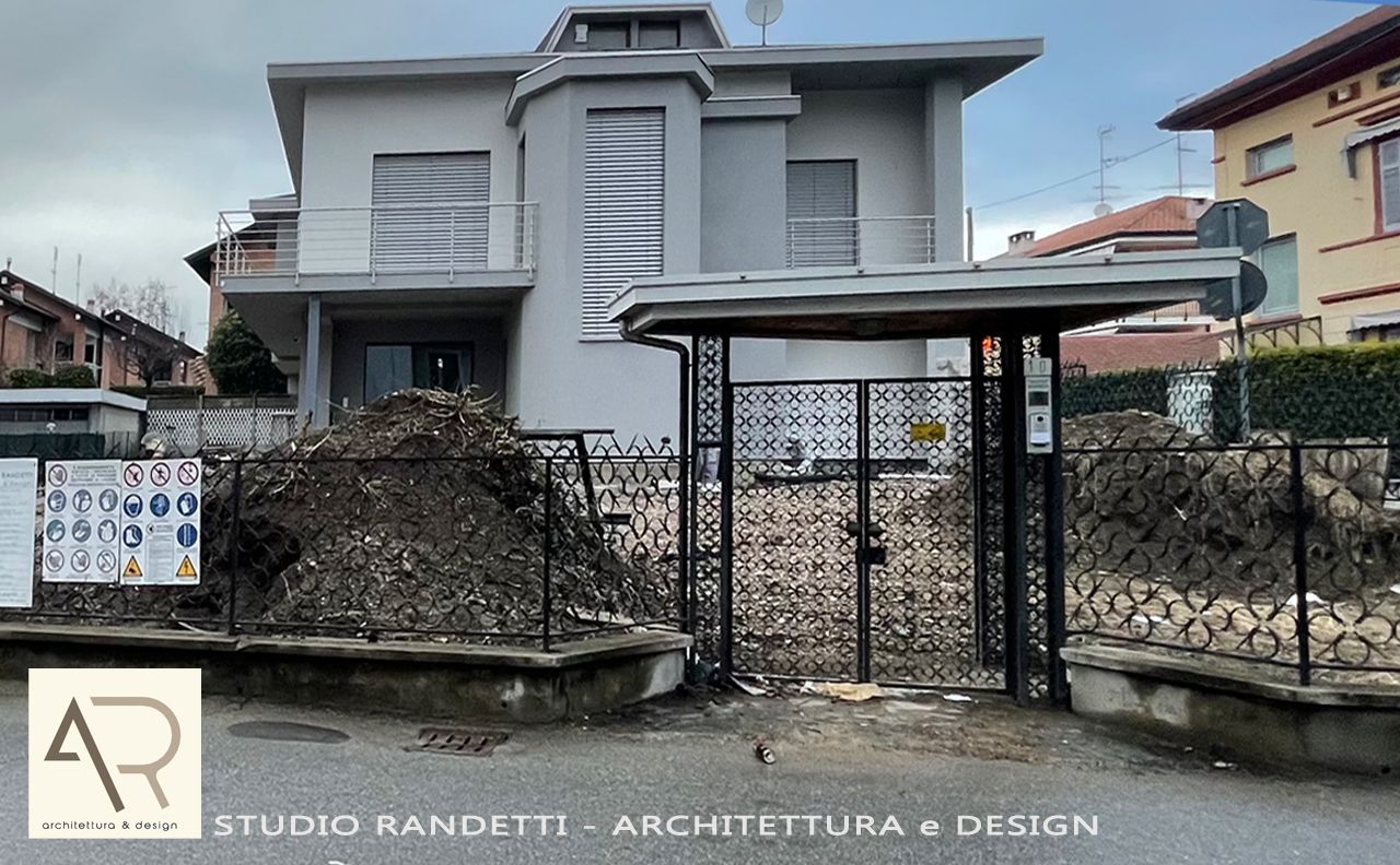 Casa moderna grigia a due piani con recinzione in pietra e cancello in metallo in una strada residenziale