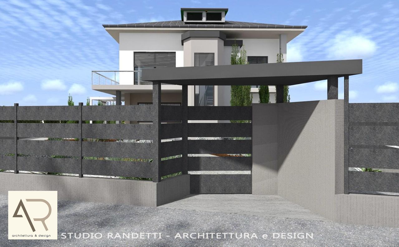 Casa moderna a due piani, nascosta dietro un cancello a persiana scuro e una recinzione in cemento, con un piccolo giardino antistante e cielo azzurro.
