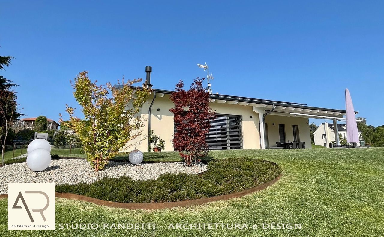 Casa moderna a un solo piano con tetto spiovente, prato curato e cielo azzurro.