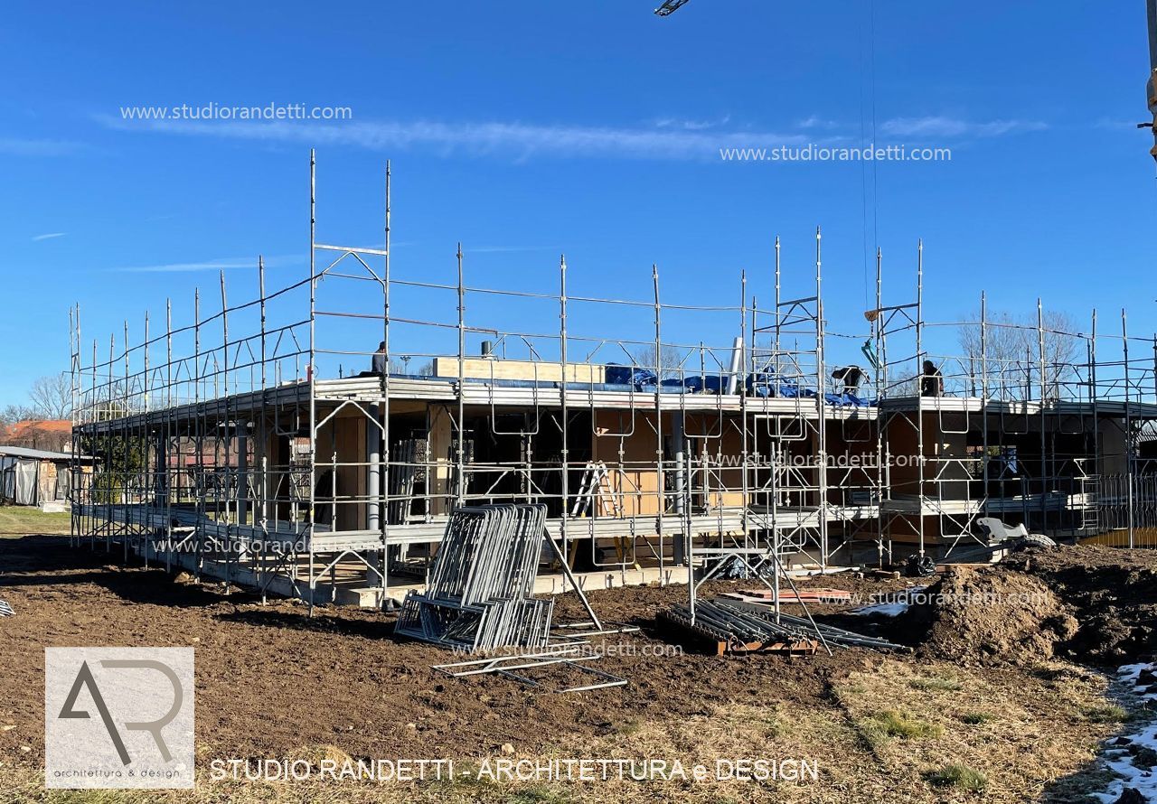 Casa a un solo piano in costruzione con impalcature sotto un cielo azzurro e limpido.