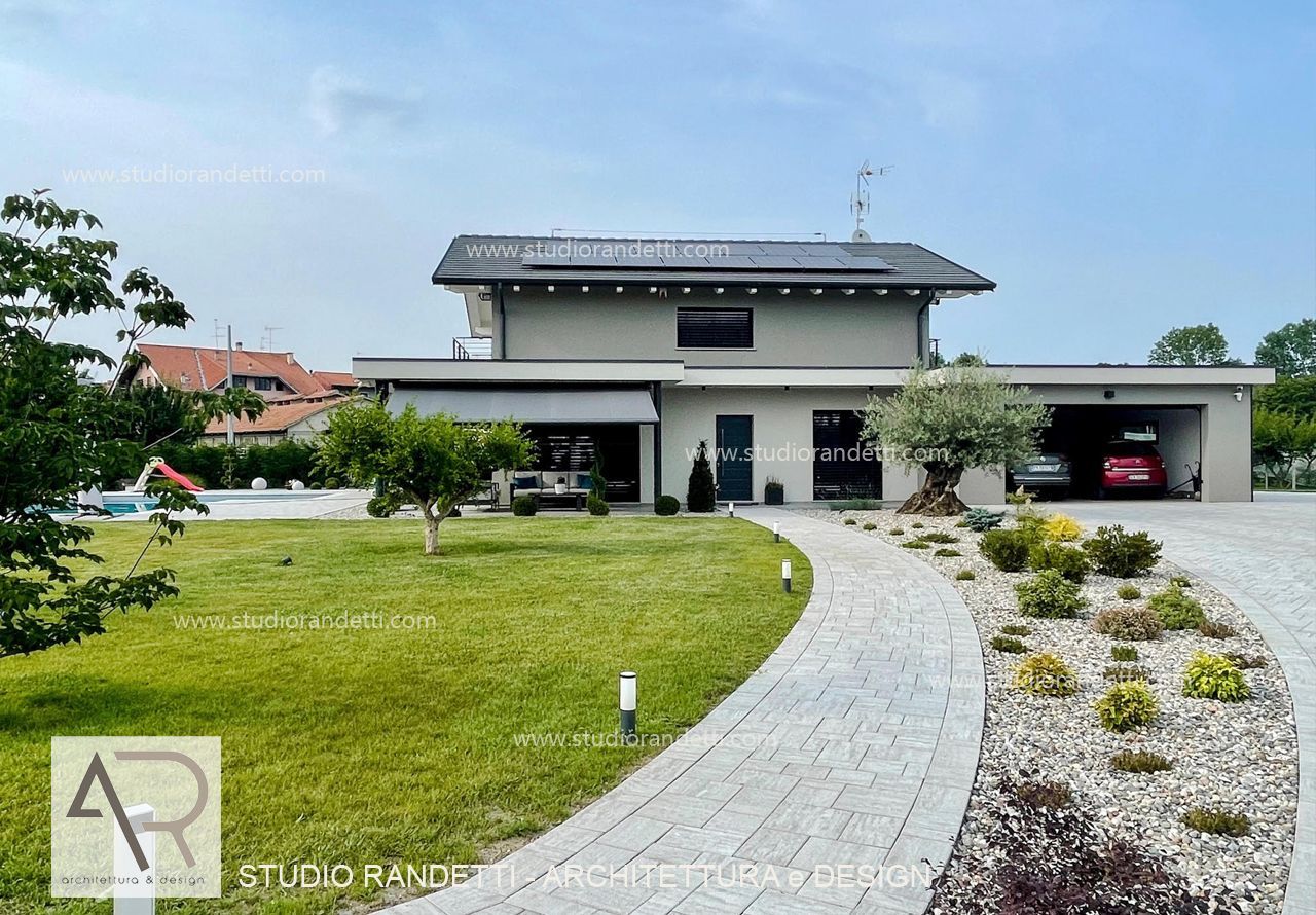 Casa moderna a due piani con vialetto d'accesso curvo in pietra e prato anteriore curato.
