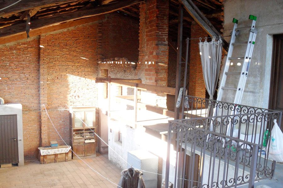 Soffitta luminosa con mattoni a vista, travi in ​​legno, scala e ringhiera in metallo in un ambiente loft.