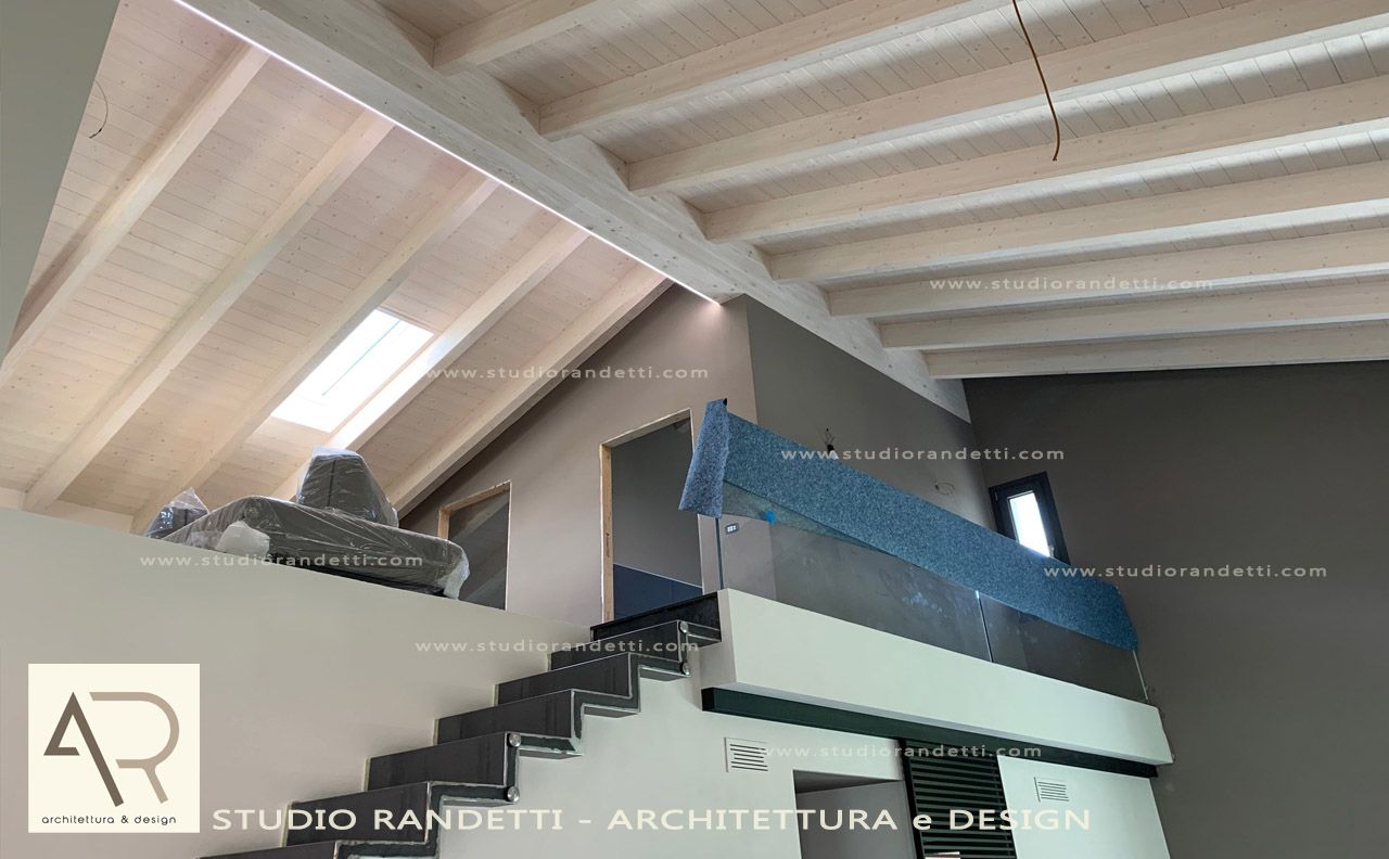 Interno della soffitta con travi in ​​legno a vista, lucernario e mobili o oggetti riposti accatastati lungo la parete.