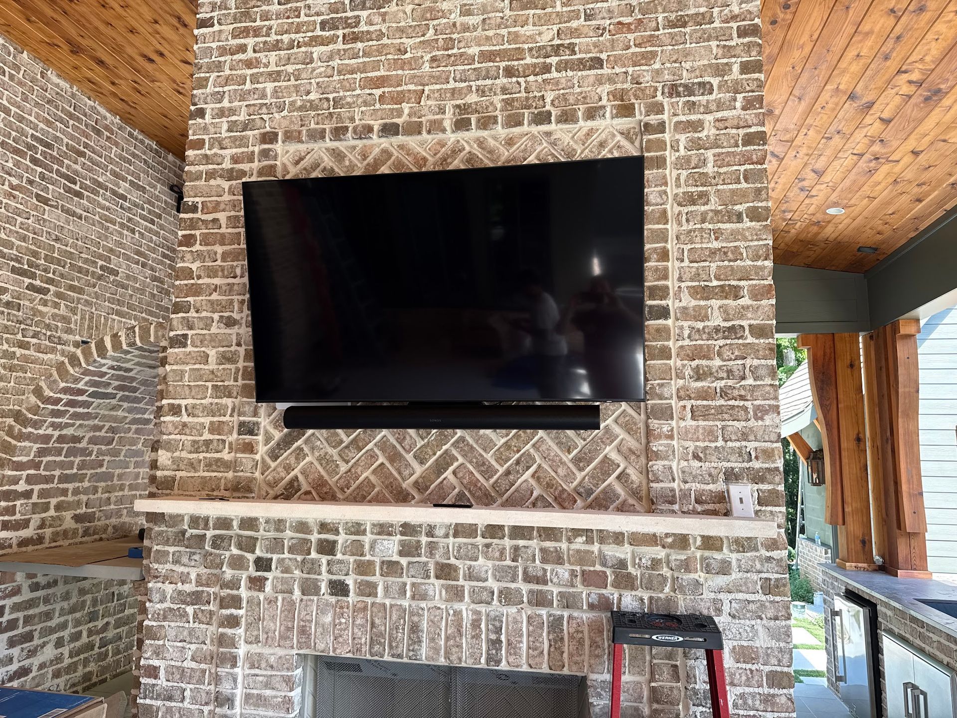 Large TV mounted on a brick fireplace; soundbar below.