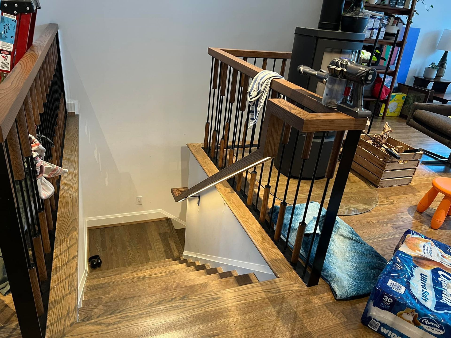 Staircase with wood and black metal railing, leading down to a lower level with wood flooring.