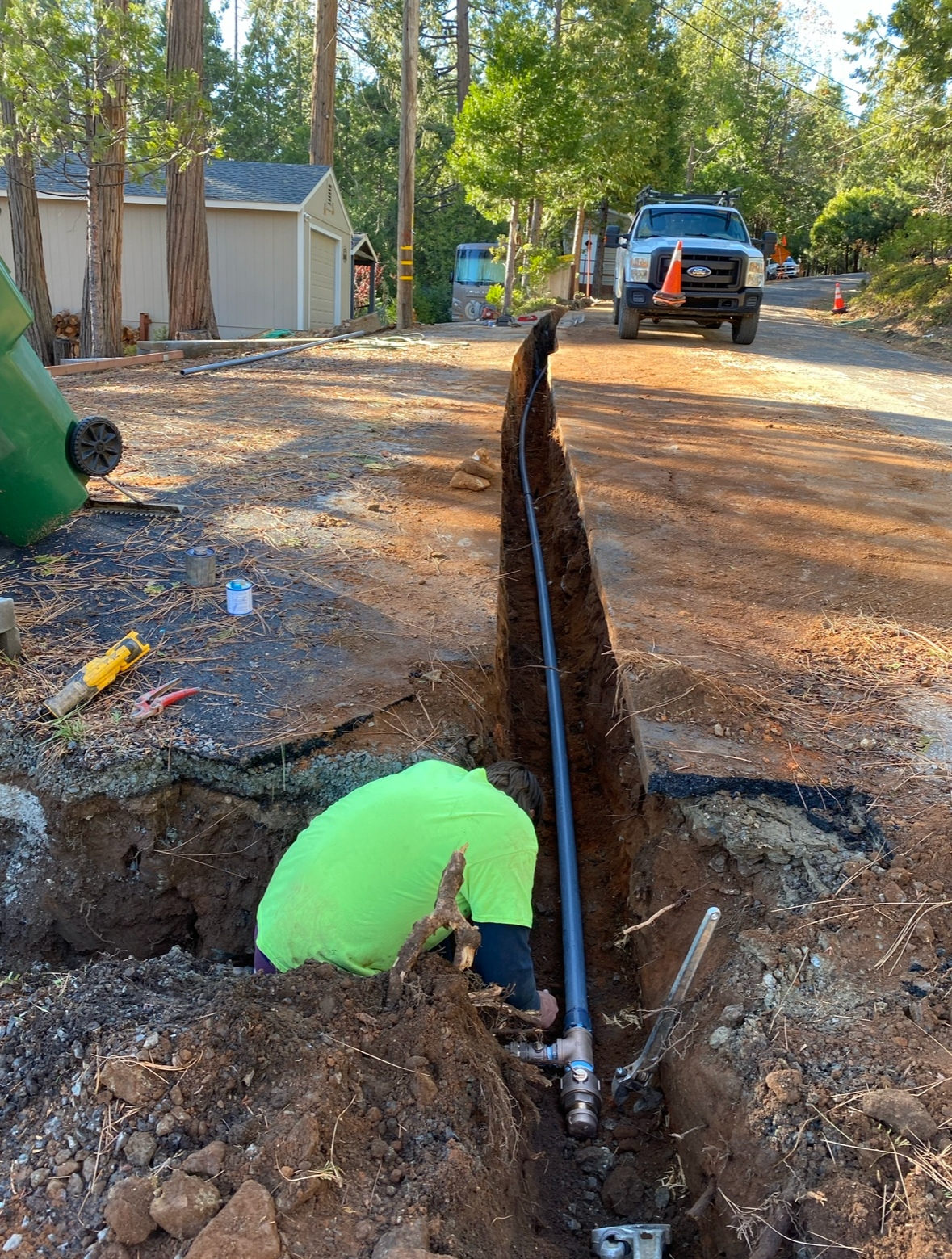A man is digging a hole in the ground to install a pipe.