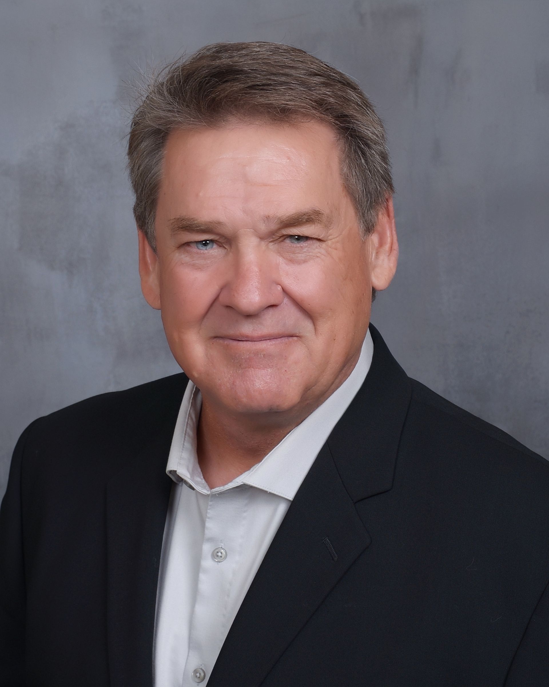 A woman wearing glasses and a black and white polka dot shirt is smiling for the camera.