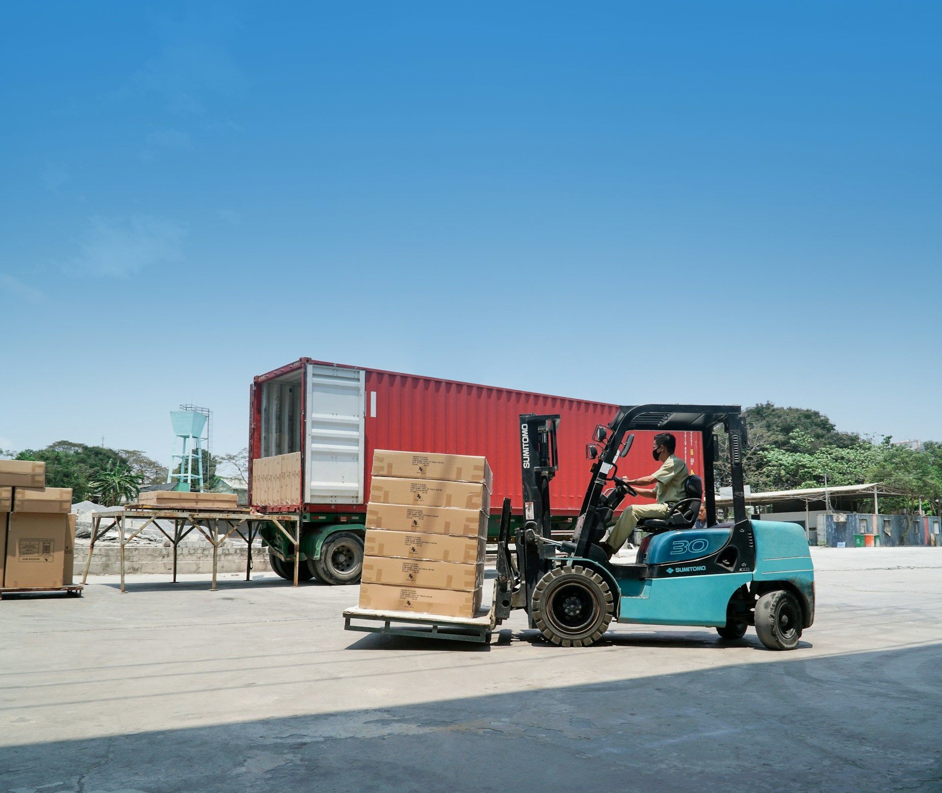 Man and woman looking at paperwork in a warehouse setting, surrounded by boxes on shelves.