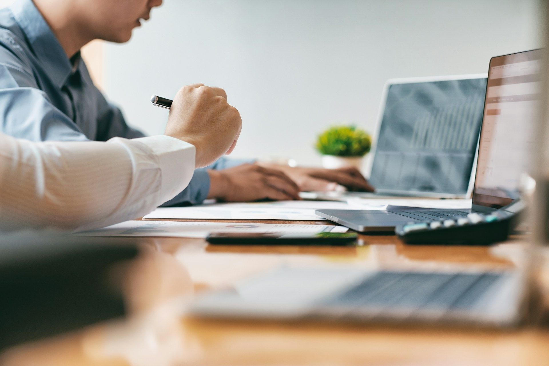 Man and woman looking at paperwork in a warehouse setting, surrounded by boxes on shelves.