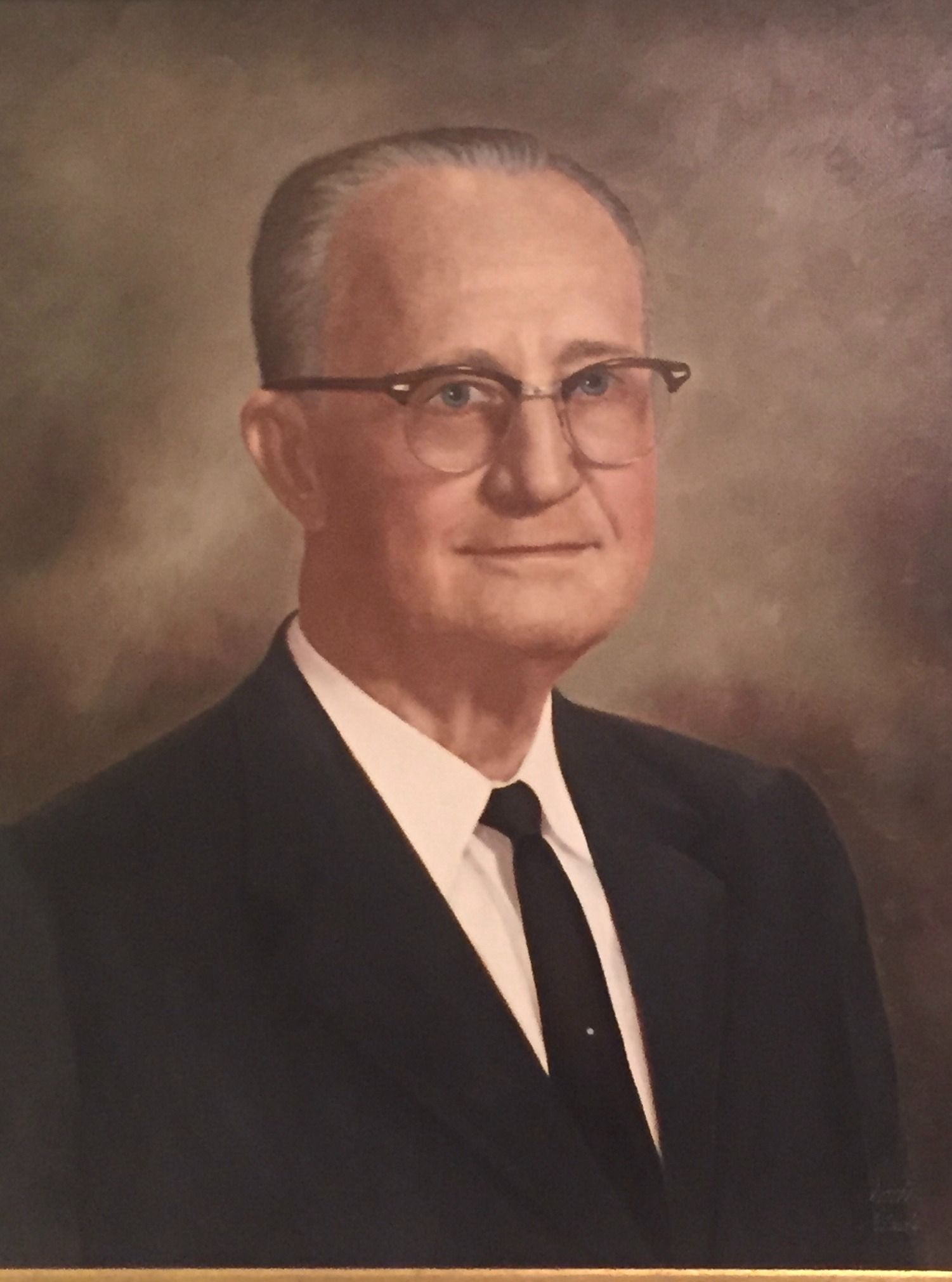 Man in a dark suit and glasses, posed portrait.