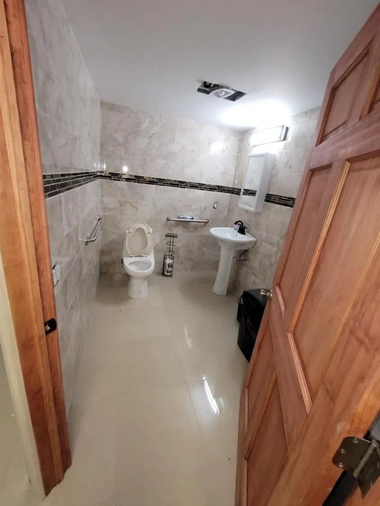 A bathroom with a toilet , sink and mirror.