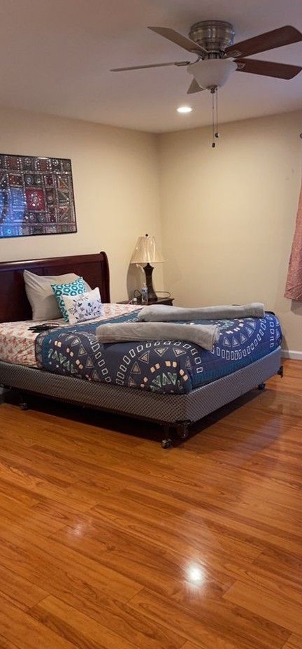 A bedroom with a large bed and a ceiling fan.