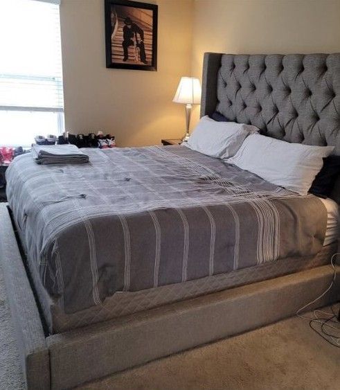 A bedroom with a large bed and a picture on the wall above it.