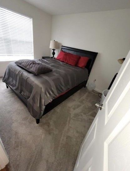 A bedroom with a bed , lamps , and a window.