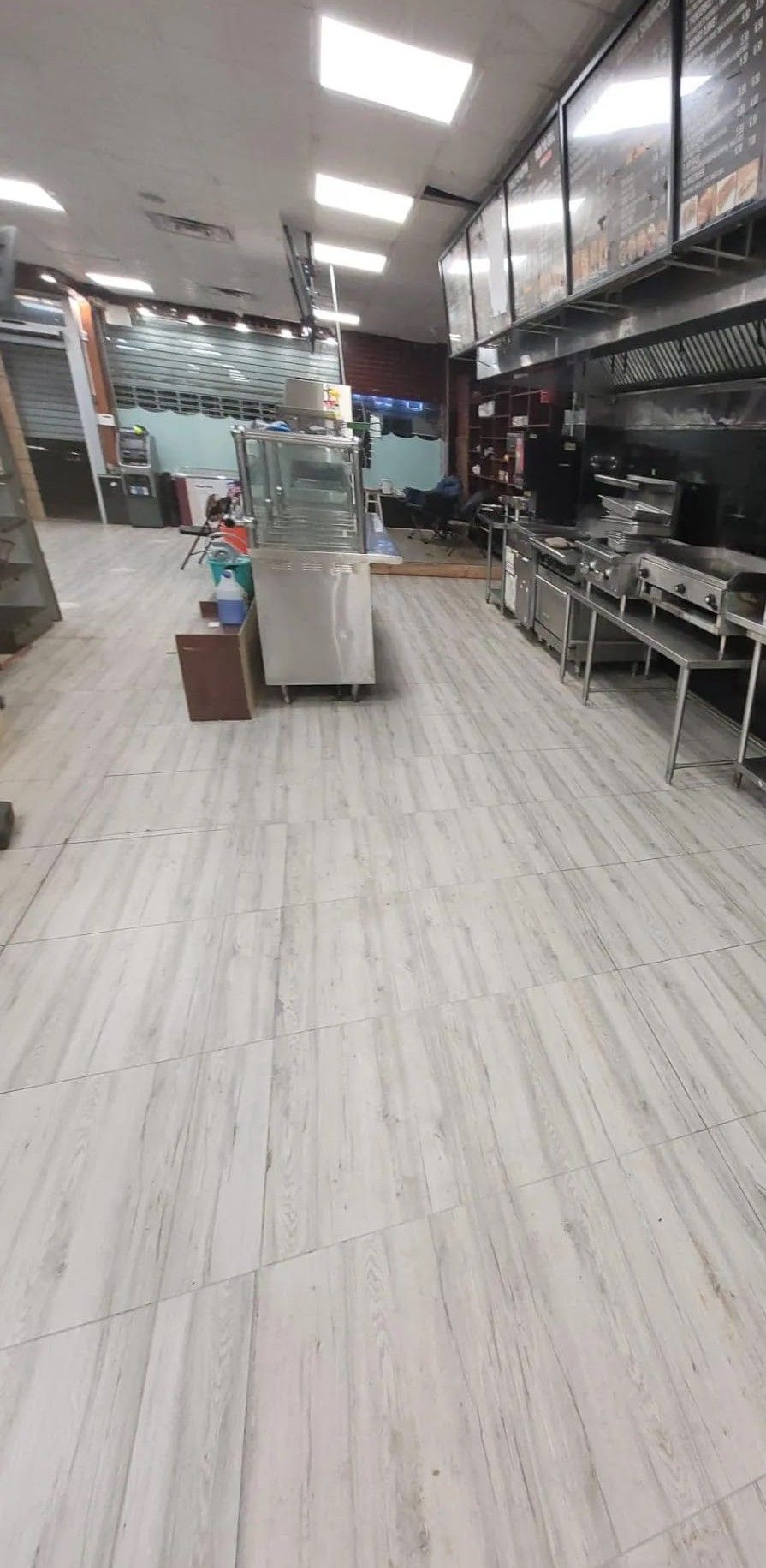 The inside of a restaurant with a wooden floor and a lot of appliances.