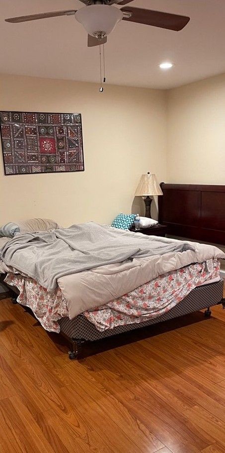 There is a bed in the middle of the room with a ceiling fan.