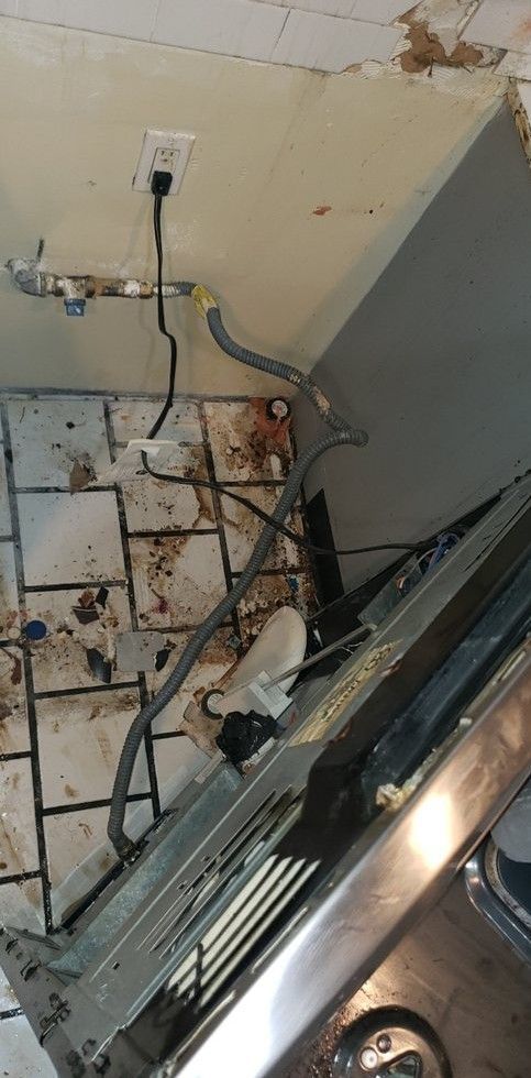 A dishwasher is sitting on a tiled floor in a kitchen.