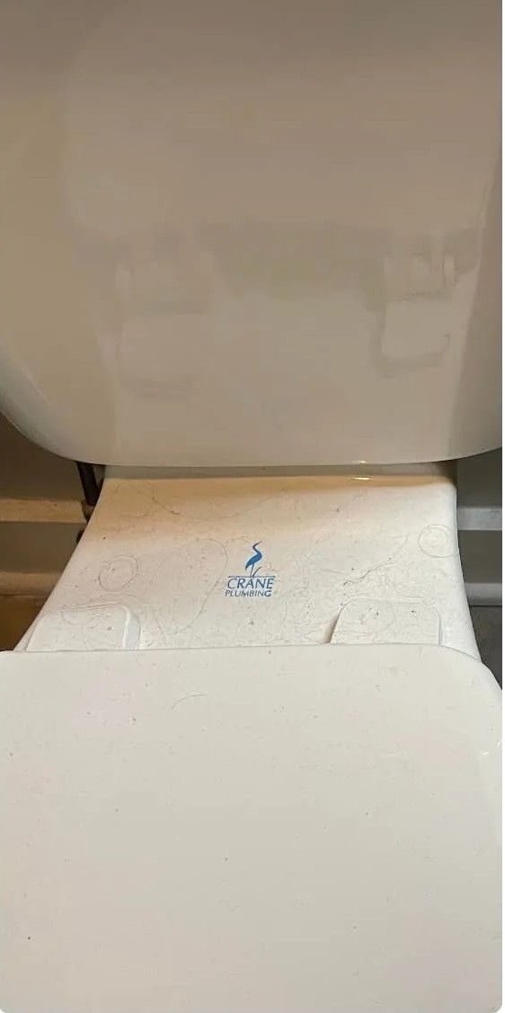 A close up of a toilet with a paper towel on it.
