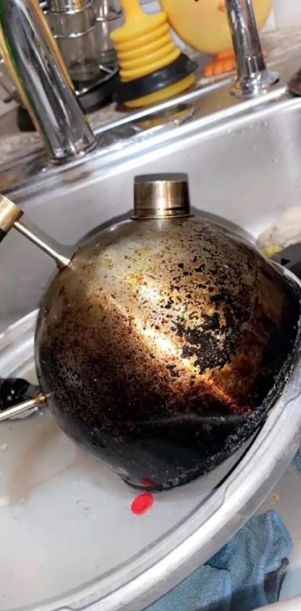 A dirty pot is sitting in a sink next to a faucet.