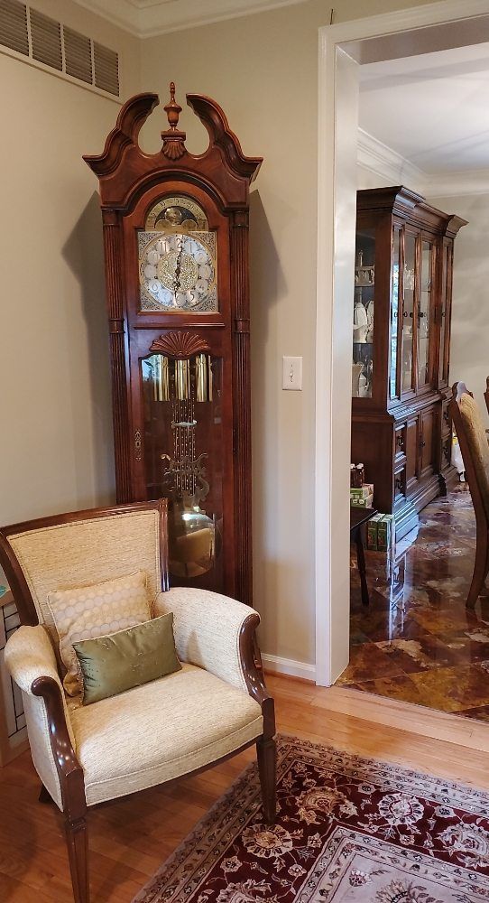 A living room with a chair and a grandfather clock.